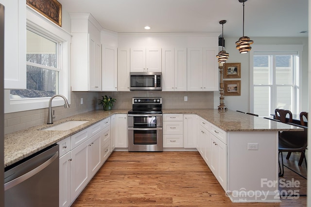 kitchen featuring sink, a breakfast bar area, white cabinetry, appliances with stainless steel finishes, and kitchen peninsula