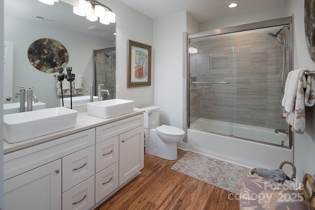 full bathroom with vanity, hardwood / wood-style flooring, combined bath / shower with glass door, and toilet