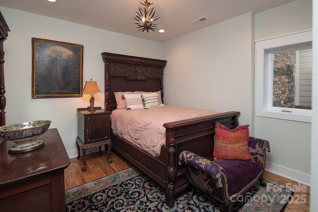 bedroom with an inviting chandelier and light hardwood / wood-style flooring