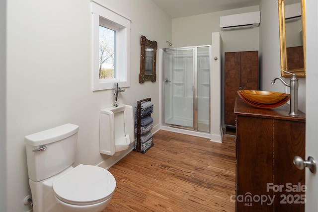 bathroom featuring hardwood / wood-style flooring, a shower with door, toilet, and a wall mounted AC