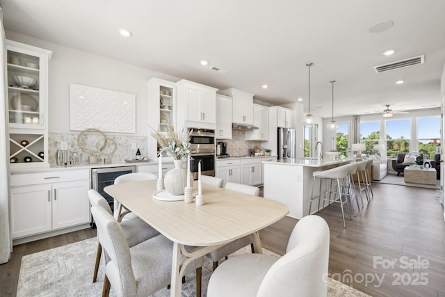 dining room featuring wine cooler, ceiling fan, and dark wood-type flooring