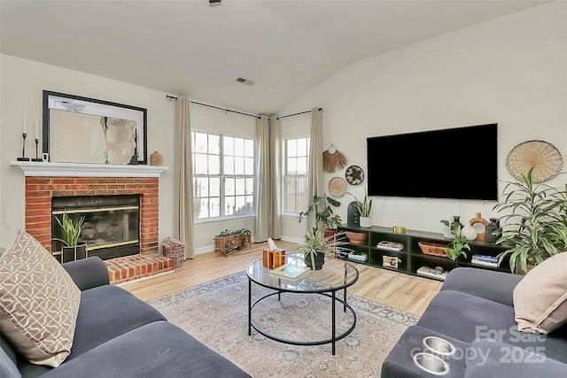 living room featuring lofted ceiling, a fireplace, and hardwood / wood-style flooring