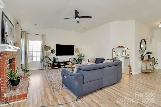 living room featuring a brick fireplace, vaulted ceiling, light hardwood / wood-style floors, and ceiling fan