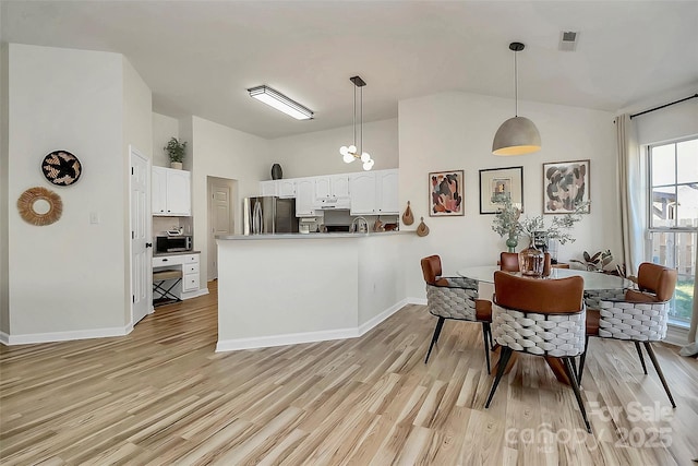 kitchen featuring pendant lighting, white cabinetry, stainless steel appliances, light hardwood / wood-style floors, and kitchen peninsula