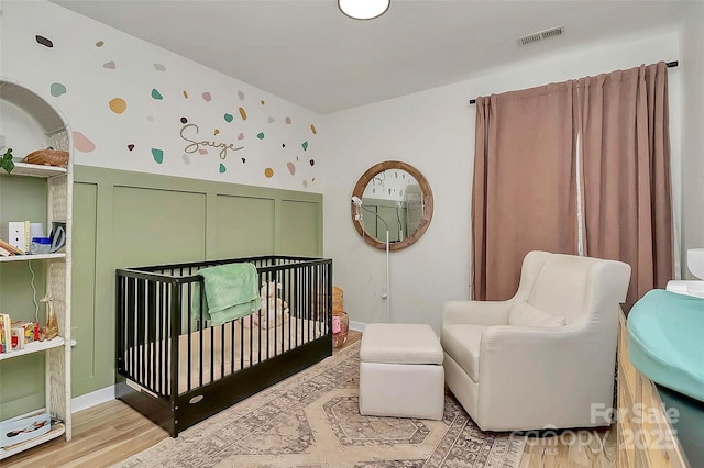 bedroom featuring a crib and light hardwood / wood-style floors