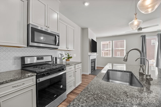 kitchen featuring stainless steel appliances, white cabinetry, dark stone counters, and sink