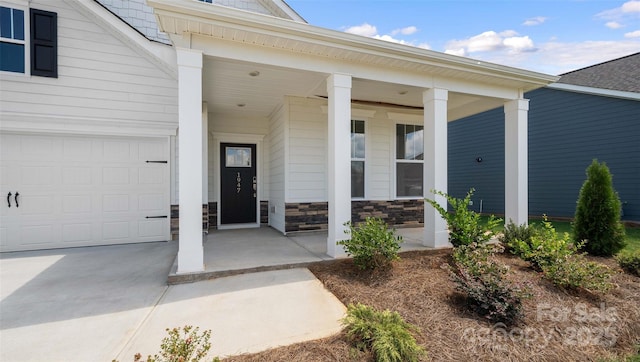 view of exterior entry featuring a garage and covered porch