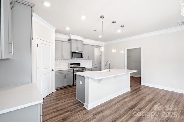 kitchen featuring a center island with sink, appliances with stainless steel finishes, gray cabinetry, pendant lighting, and sink