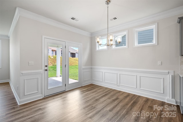 unfurnished dining area featuring ornamental molding, a notable chandelier, and dark wood-type flooring