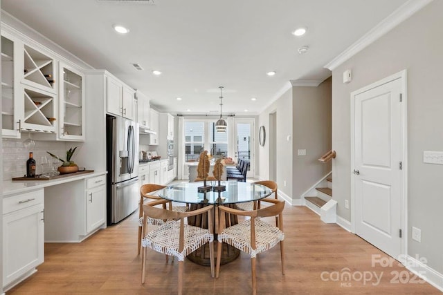 dining area featuring ornamental molding and light hardwood / wood-style floors