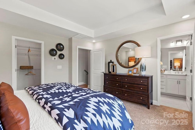 carpeted bedroom with a raised ceiling, a closet, connected bathroom, and a spacious closet