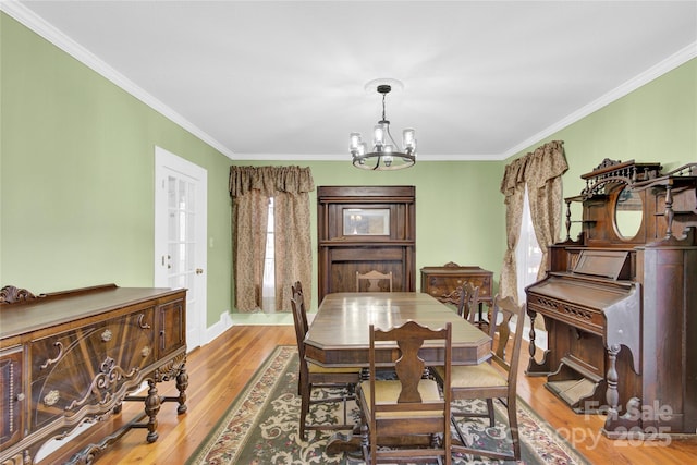 dining area with light hardwood / wood-style flooring, crown molding, and an inviting chandelier