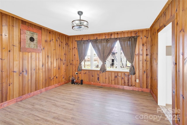 unfurnished room featuring wooden walls and light wood-type flooring