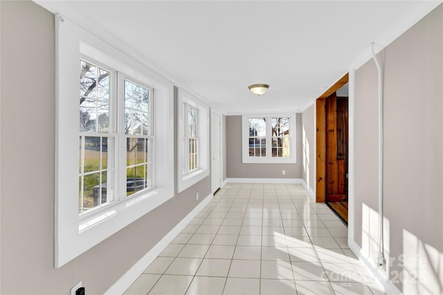 hallway with light tile patterned floors and crown molding