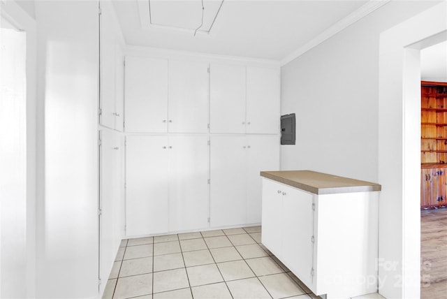 interior space with light tile patterned floors, white cabinetry, ornamental molding, and electric panel