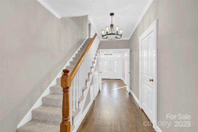 entrance foyer with dark hardwood / wood-style floors, a chandelier, and ornamental molding