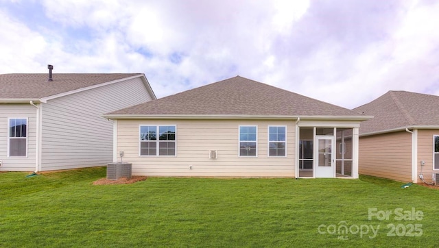 rear view of house featuring central air condition unit, a lawn, and a sunroom