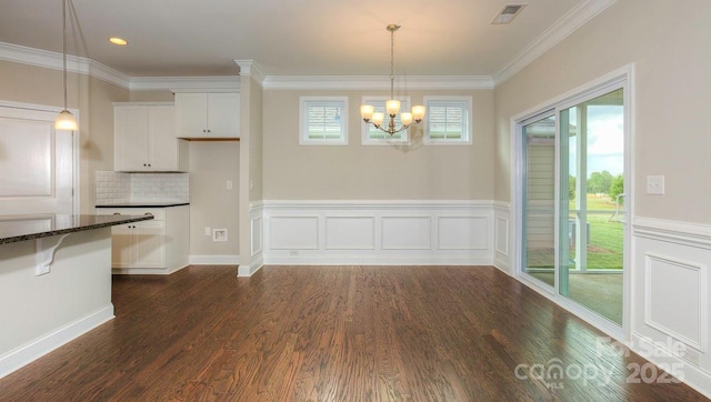 unfurnished dining area featuring dark hardwood / wood-style flooring, a chandelier, and ornamental molding