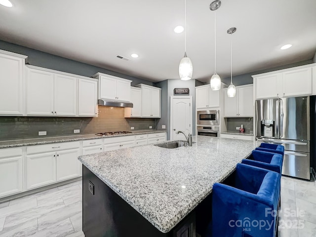 kitchen featuring sink, a center island with sink, stainless steel appliances, and tasteful backsplash