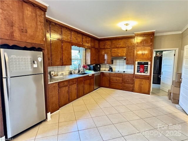 kitchen featuring appliances with stainless steel finishes, sink, backsplash, light tile patterned flooring, and crown molding