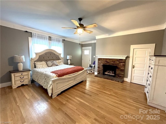 bedroom with ceiling fan, crown molding, light hardwood / wood-style floors, and a fireplace