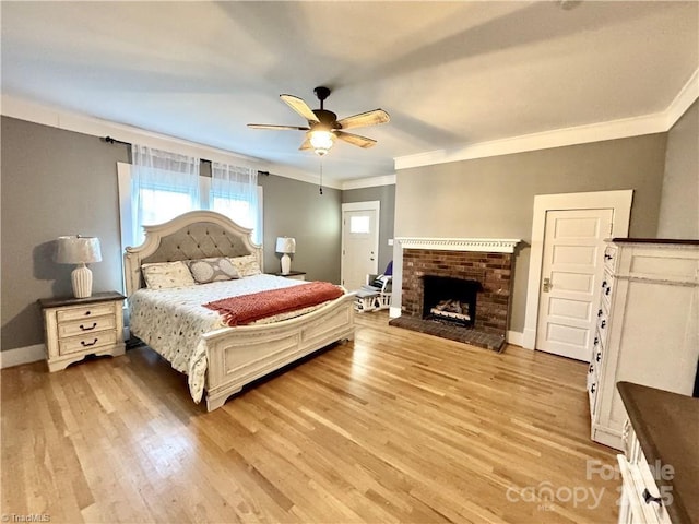 bedroom featuring ceiling fan, ornamental molding, light hardwood / wood-style floors, and a fireplace