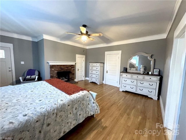 bedroom featuring wood-type flooring, a brick fireplace, and ceiling fan