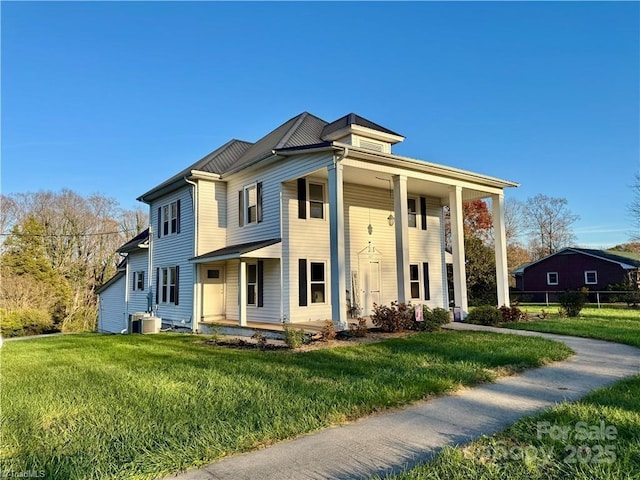 view of front of home featuring covered porch, a front yard, and central AC unit