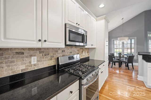 kitchen with white cabinetry, stainless steel appliances, vaulted ceiling, pendant lighting, and light hardwood / wood-style flooring