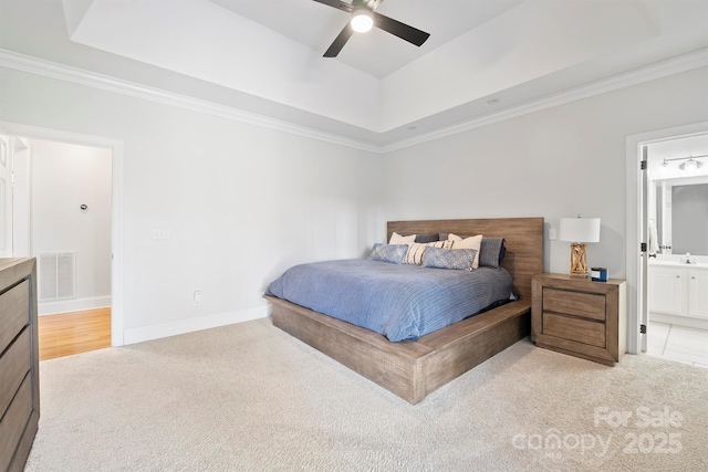 carpeted bedroom featuring ceiling fan, ensuite bathroom, ornamental molding, and a raised ceiling