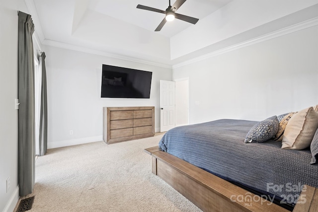 carpeted bedroom with ceiling fan, ornamental molding, and a raised ceiling