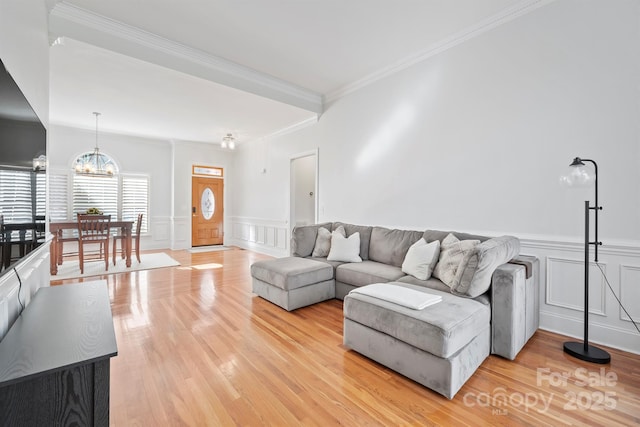 living room featuring an inviting chandelier, crown molding, and light hardwood / wood-style floors