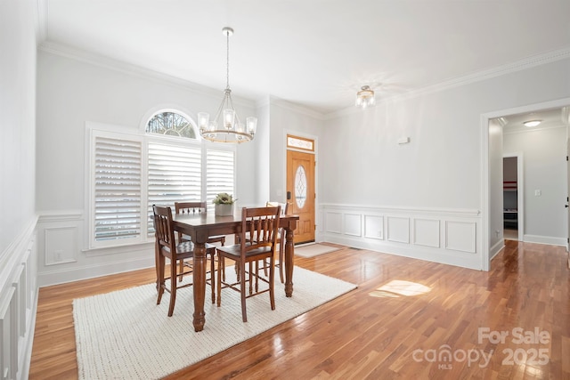 dining space featuring light wood-type flooring, an inviting chandelier, and ornamental molding