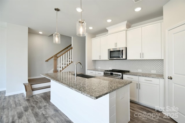 kitchen featuring appliances with stainless steel finishes, an island with sink, white cabinets, and sink