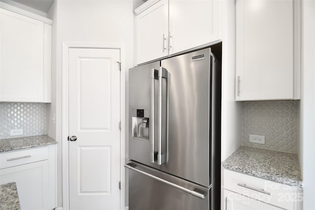 kitchen with high end fridge, white cabinetry, light stone counters, and decorative backsplash