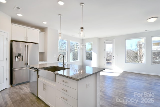 kitchen with stainless steel appliances, white cabinets, sink, and light stone countertops