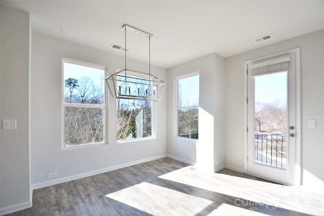 unfurnished dining area featuring an inviting chandelier and dark hardwood / wood-style flooring