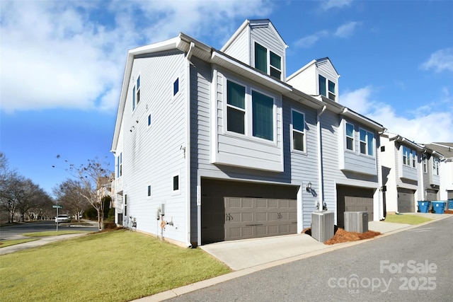 view of front of home with a front yard, a garage, and central air condition unit