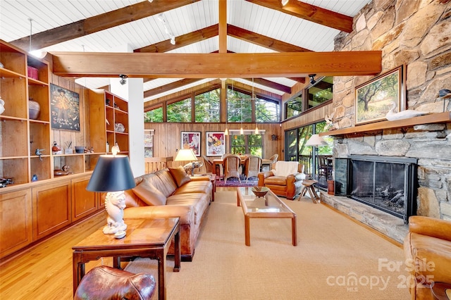 living room with wood walls, high vaulted ceiling, light wood-type flooring, beamed ceiling, and a fireplace