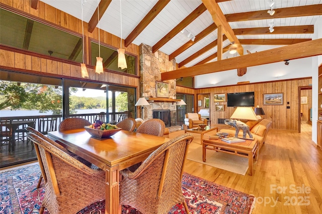 dining area with beam ceiling, wood walls, high vaulted ceiling, hardwood / wood-style flooring, and a fireplace