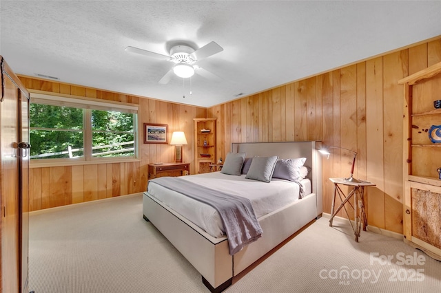 carpeted bedroom with ceiling fan and wood walls