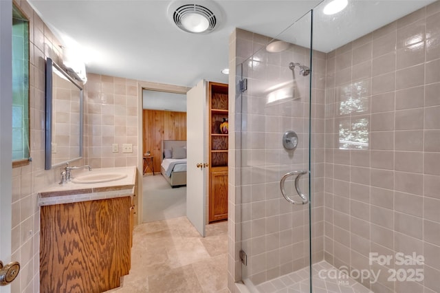 bathroom with vanity, tile walls, and walk in shower