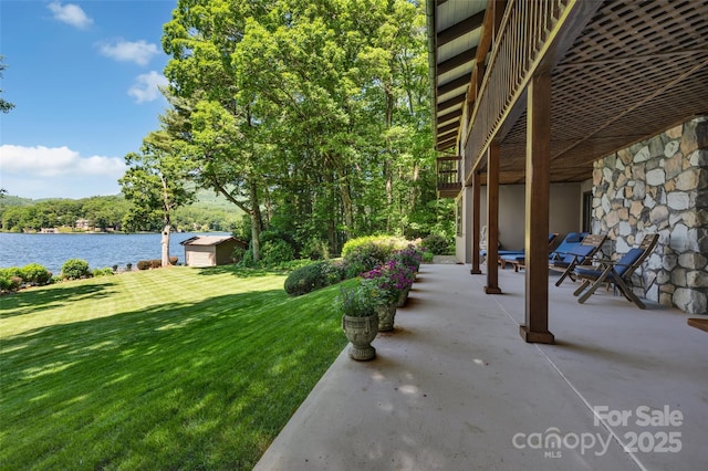 view of yard with a shed, a patio, and a water view