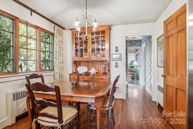 dining space with radiator heating unit, dark wood-type flooring, a chandelier, and ornamental molding