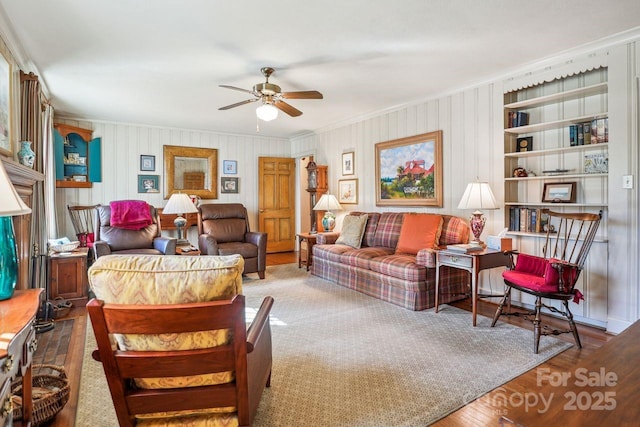 living room featuring ceiling fan, hardwood / wood-style floors, built in features, and crown molding