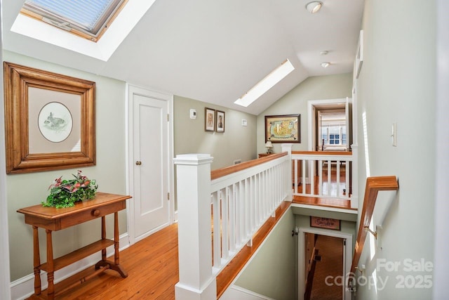 hall featuring vaulted ceiling with skylight and light hardwood / wood-style flooring