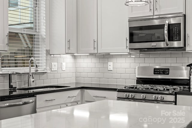 kitchen featuring sink, backsplash, white cabinets, and stainless steel appliances