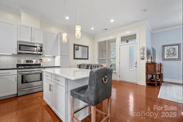 kitchen with pendant lighting, a kitchen island, white cabinetry, stainless steel appliances, and a breakfast bar