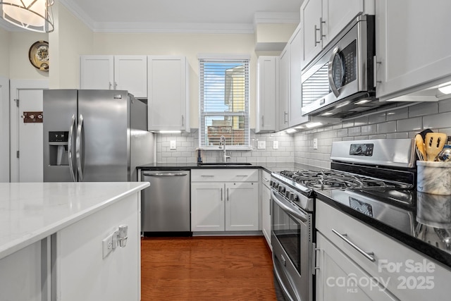 kitchen featuring tasteful backsplash, dark stone countertops, sink, white cabinetry, and appliances with stainless steel finishes