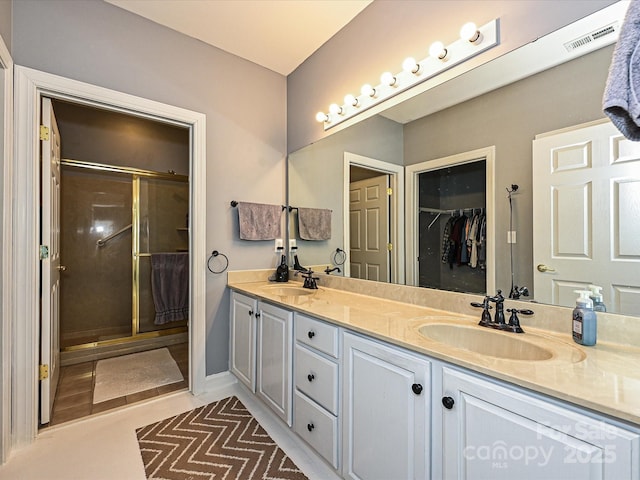 bathroom with a shower with door, tile patterned floors, and vanity